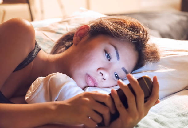 Woman using mobile phone in bed before sleep stock photo