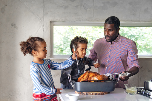 Fathers preparing thanksgiving turkey with his kids
