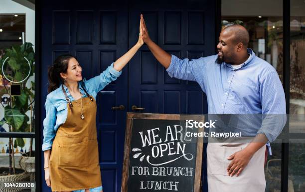 Cheerful Business Owners Standing With Open Blackboard Stock Photo - Download Image Now