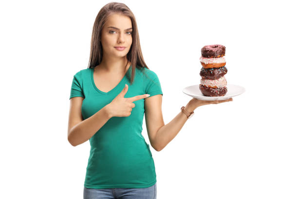istock Beautiful young woman holding a plate with donuts and pointing 1044280382
