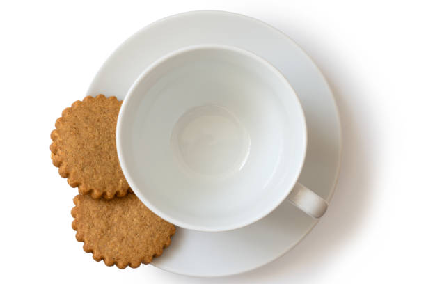 an empty white ceramic cup and saucer with two gingerbread biscuits isolated on white from above. - two objects cup saucer isolated imagens e fotografias de stock