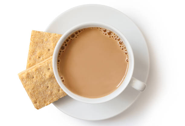 a cup of tea with milk and two square shortbread biscuits isolated on white from above. white ceramic cup and saucer. - two objects cup saucer isolated imagens e fotografias de stock