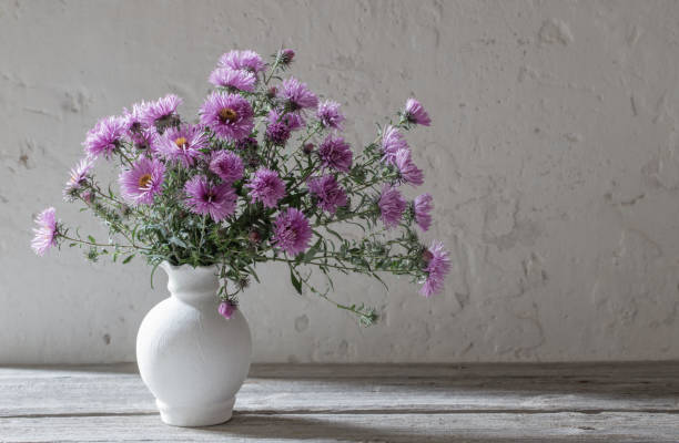 istock violet flowers in white vase on old background 1044283698