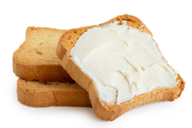istock Melba toast with cream cheese lying on two plain toasts isolated on white. 1044284160