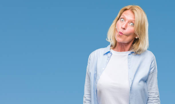 istock Middle age blonde woman over isolated background making fish face with lips, crazy and comical gesture. Funny expression. 1044288256