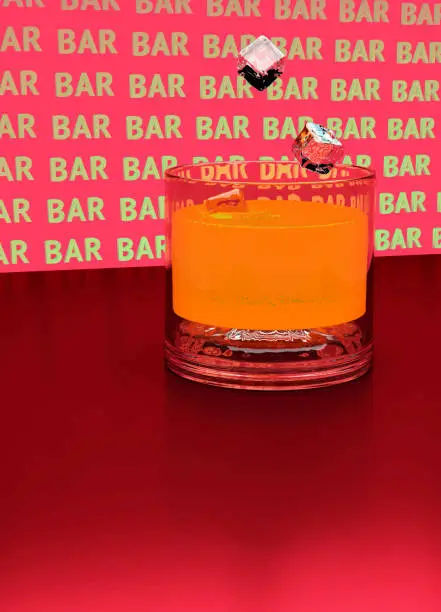 3D illustration. Bar. Ice cubes fall into a glass of orange juice