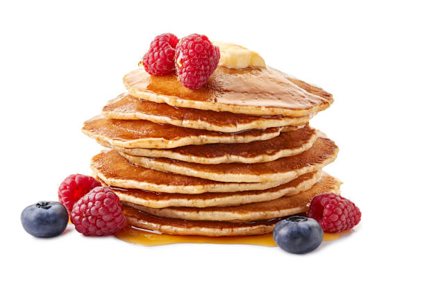 Stack of pancakes with maple syrup and fresh berries on white