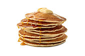 Stack of pancakes with butter and a flowing maple syrup on white