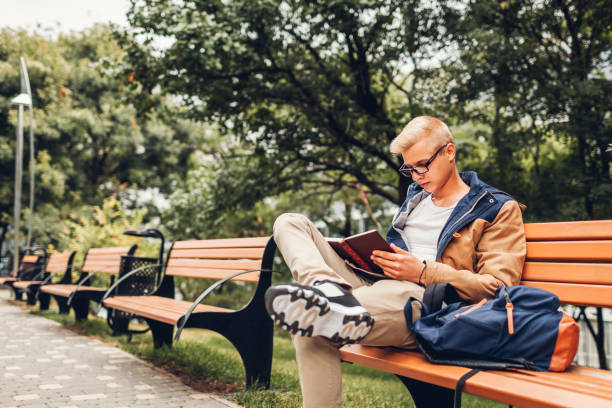 istock College student with backpack reading book walking in autumn park sitting on bench 1044306910