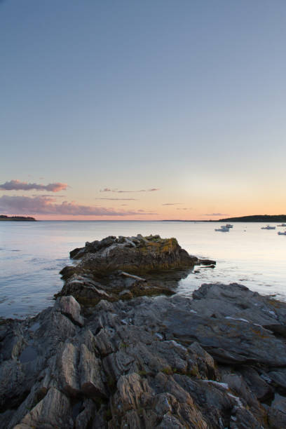 istock Boats at Sunset Beyond a Rocky Peninsula 1044319386