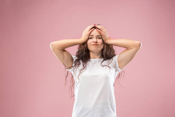 Woman having headache. Isolated over pink background.