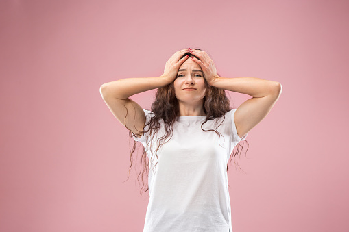 Woman having headache. Isolated on pink background. Businesswoman standing with pain isolated on trendy studio background. Female half-length portrait. Human emotions, facial expression concept. Front