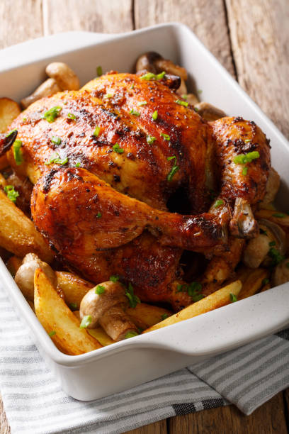 istock Appetizing baked chicken with mushrooms and potatoes close-up in a baking dish. Vertical 1044322852