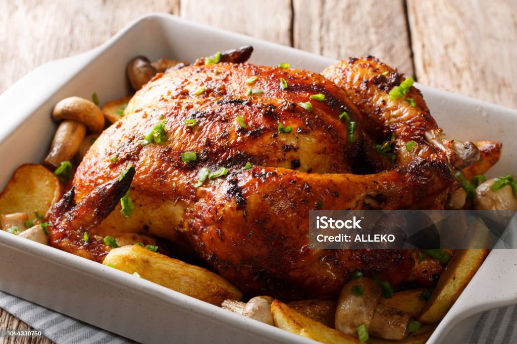 grilled chicken with mushrooms and potatoes close-up in a baking dish. horizontal Whole grilled chicken with mushrooms and potatoes close-up in a baking dish. horizontal Turkey Meat Stock Photo