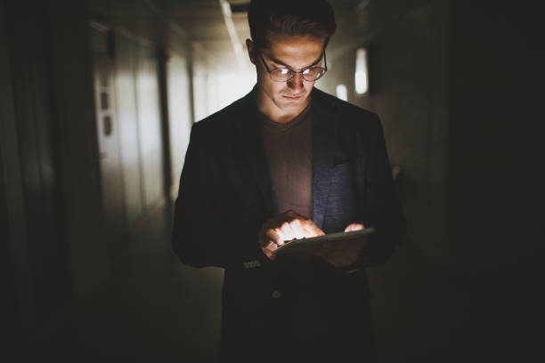 istock Hipster businessman working on a digital tablet in a dark hallway 1044334126