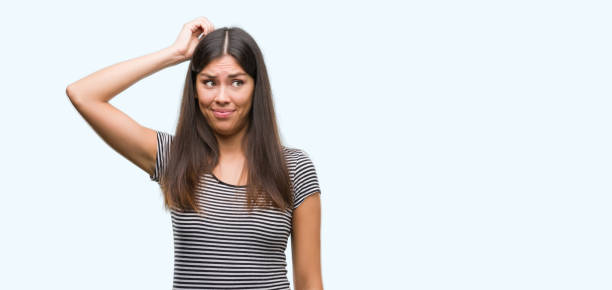 istock Young beautiful hispanic woman confuse and wonder about question. Uncertain with doubt, thinking with hand on head. Pensive concept. 1044335290