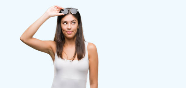 istock Young beautiful hispanic wearing sunglasses smiling looking side and staring away thinking. 1044335920