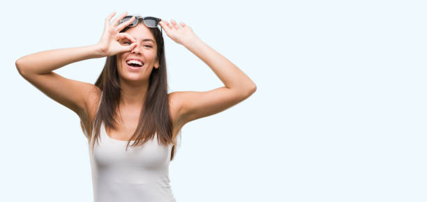 istock Young beautiful hispanic wearing sunglasses doing ok gesture with hand smiling, eye looking through fingers with happy face. 1044336066