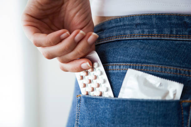 経口避妊薬とブルー ジーンズのポケットにコンドームの女性。 - condom contraceptive sensuality healthcare and medicine ストックフォトと画像