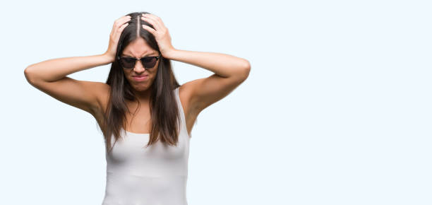 istock Young beautiful hispanic wearing sunglasses suffering from headache desperate and stressed because pain and migraine. Hands on head. 1044336626