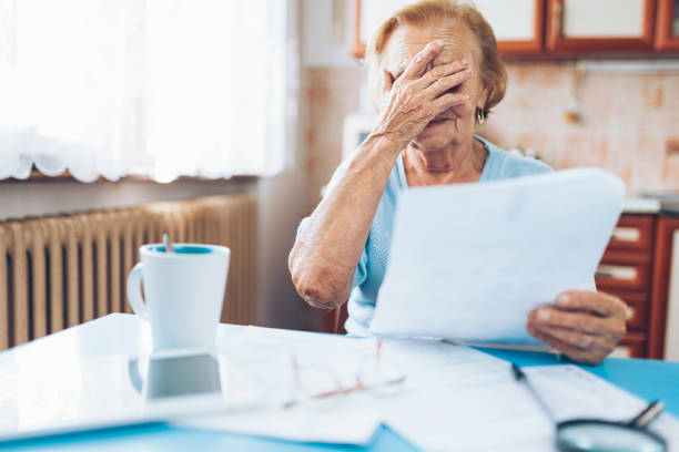 istock Elderly woman looking at her utility bills 1044338538