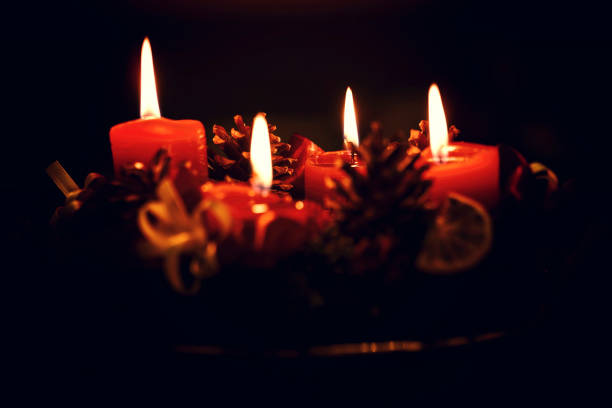 istock Low light Christmas Advent wreath with burning red candles on black background 1044340404