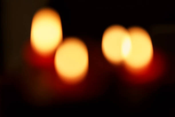 Defocused low light burning red candles on black background
