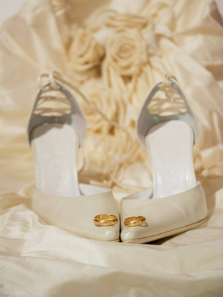 anéis de casamento e sapatos femininos com um vestido no fundo - couple gold pair vertical - fotografias e filmes do acervo
