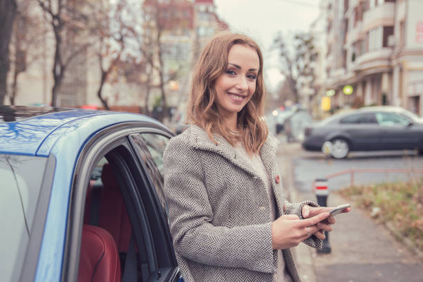 istock Woman using mobile phone standing beside her car 1044357782
