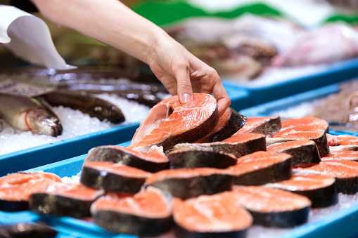 Joven vendedor elegir una paz de salmón en el mercado. photo