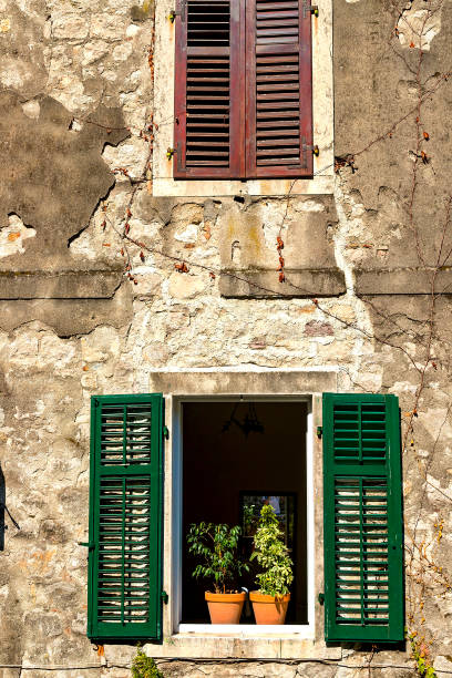 istock Authentic house with a stone wall, with beautiful old open windows and with brown shutters, and with vases on the window. Montenegro 1044372900