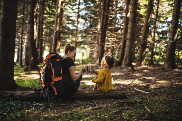 Family of two enjoying a beverage in a pine forest while hiking
