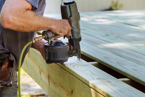Installing Wood on deck, patio construction man using pneumatic nailer air gun