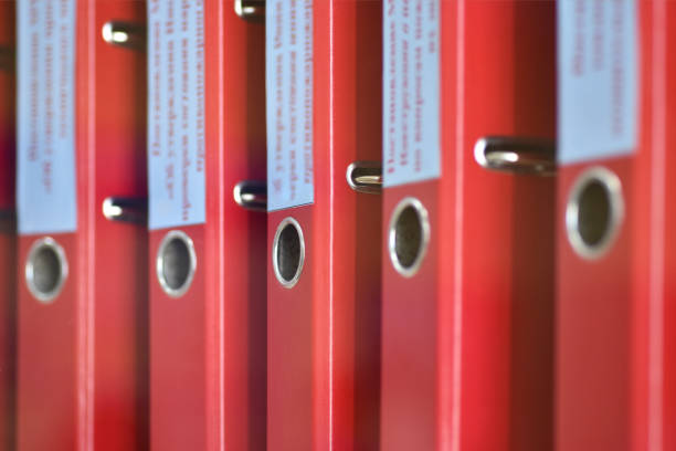Red large folders files with inscriptions for storing office documents stand vertically on shelf