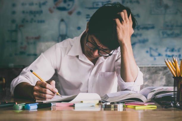 istock Young Asian student man sitting at desk in home studying and reading, doing homework and lesson practice preparing exam to entrance, education concept 1044395198