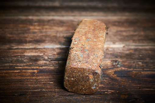 Head of an old rusty hammer without haft lying on old wooden board
