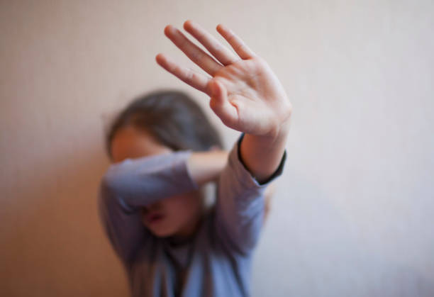 A little girl protects herself with her palm and covers her face A little girl protects herself with her palm torture photos stock pictures, royalty-free photos & images