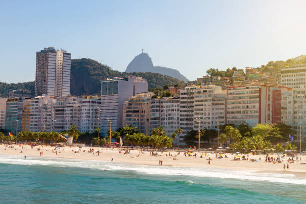 Hundreds of tourists enjoy Copacabana beach during the beginning of the afternoon. In the background, the Corcovado hill and the Christ the Redeemer statue Rio de Janeiro, Brazil - August 20, 2018: Hundreds of tourists enjoy Copacabana beach during the beginning of the afternoon. In the background, the Corcovado hill and the Christ the Redeemer statue copacabana rio de janeiro photos stock pictures, royalty-free photos & images
