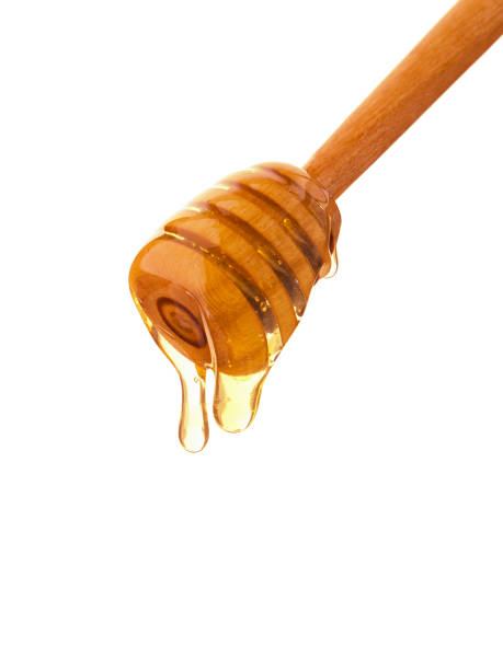 istock Isolated bee honey drops on wooden stick 1044405572