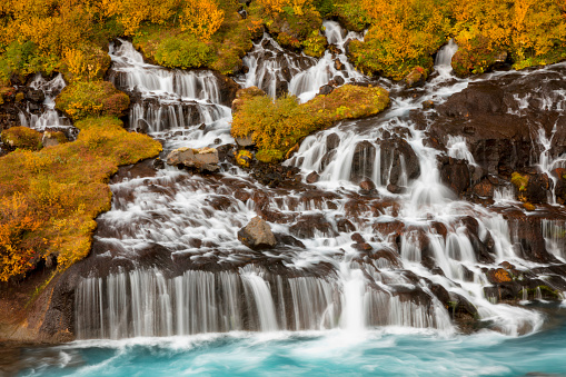 The lava field that Hraunfossar trickles through flowed from an eruption of one of the volcanoes lying under the nearby glacier of Langjökull, the second largest ice-cap in Iceland. The waterfalls pour into the Hvítá river from ledges of less porous rock in the lava.