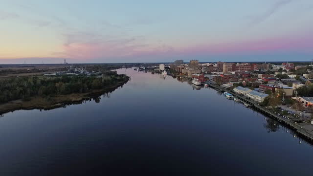 DRONE. Aerial view of historic downtown Wilmington, the USS Carolina, and the Cape Fear River during majestic sunset