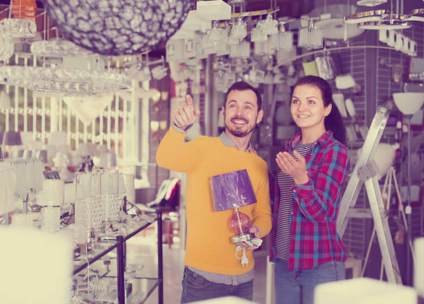 istock Smiling man points to stylish model lamp 1044417560