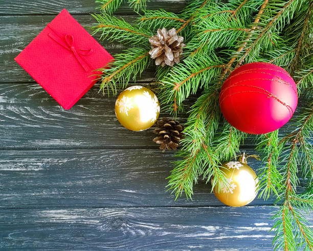istock branch of a Christmas tree, a cone, a gift box on a wooden background 1044429896