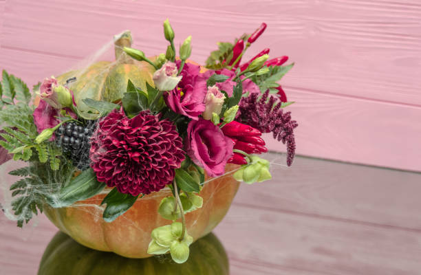 istock Halloween pumpkin with flowers and leaves on mirrow table. 1044433312