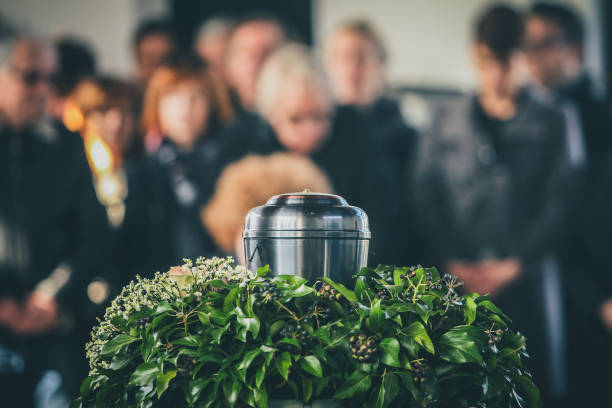 Metal urn at a funeral A metal urn with ashes of a dead person on a funeral, with people mourning in the background on a memorial service. Sad grieving moment at the end of a life. Last farewell to a person in an urn. funeral photos stock pictures, royalty-free photos & images