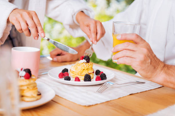 istock Mature man having nice warm pancakes with honey and berries for breakfast 1044448222