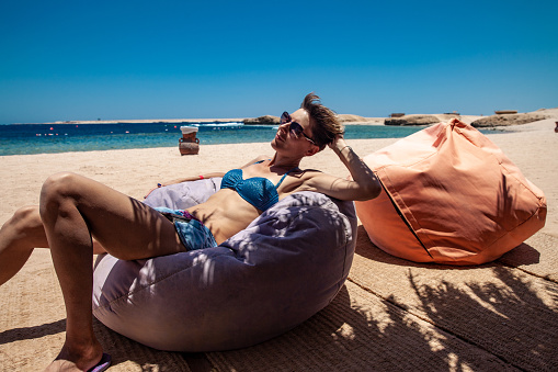 Adult Woman Relaxing on Bean Bag on Beach.