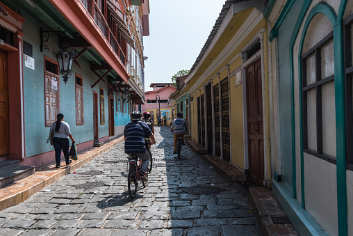 Guayaquil, Ecuador--April 15, 2018. Cyclists and pedestrians  travel along a side street in the La Pensa, the bohemian artist enclave, in Guayaquil, Ecuador.