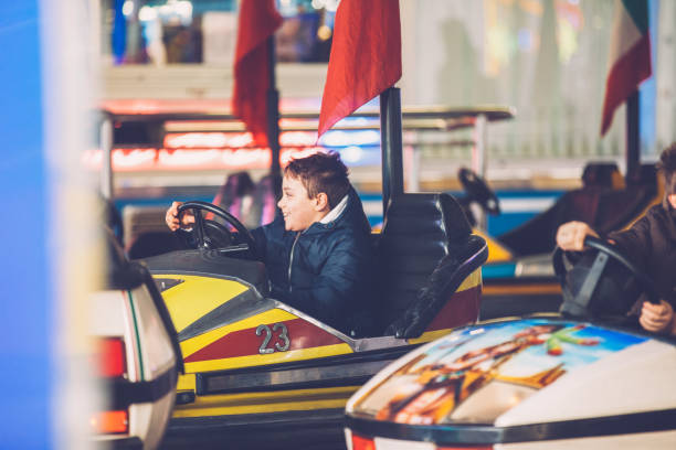 istock Young Boy Enjoying Driving a Bumper Car in Amusement Park 1044453994