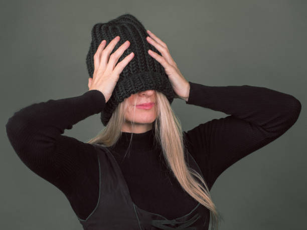 istock A shy woman pulls her a knitted hat over her face. 1044454020